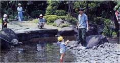 沢山の親子がきれいな池の周りで楽しんでいる様子